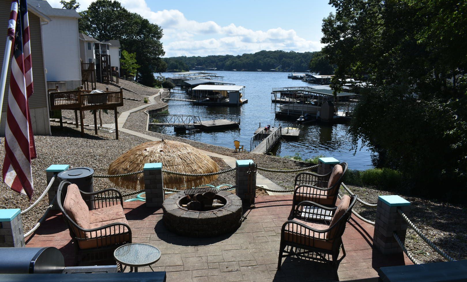 A patio with outdoor seating, a fire pit, and a view of a lake with boats.