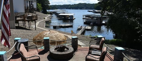 A patio with outdoor seating, a fire pit, and a view of a lake with boats.