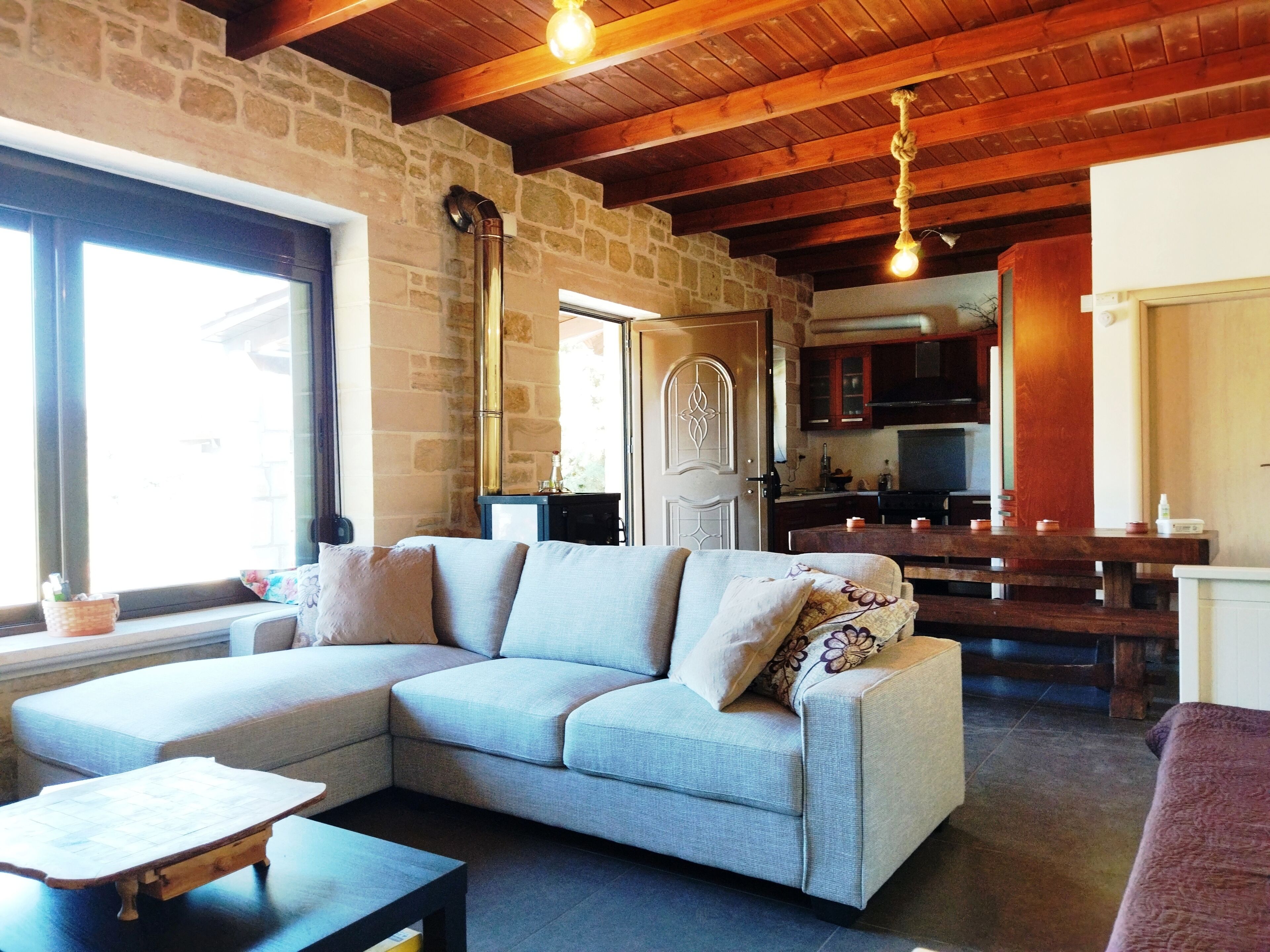 A cozy living room with a light-colored sofa, a wooden coffee table, and a stone wall.