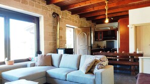 A cozy living room with a light-colored sofa, a wooden coffee table, and a stone wall. - Little House on the Prairie - Private Pool (Chania)