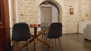 A dining area with a stone wall, a wooden table, and two chairs. - Little House on the Prairie - Private Pool (Chania)