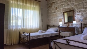 A bedroom with two beds, a wooden dresser, a mirror, and a stone wall. - Little House on the Prairie - Private Pool (Chania)