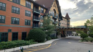 A multi-story hotel with a central courtyard, a covered walkway, and a parking area with yellow lines. - Comfy Studio at the Appalachian building - Mountain Creek Resort, Vernon, NJ (Vernon)