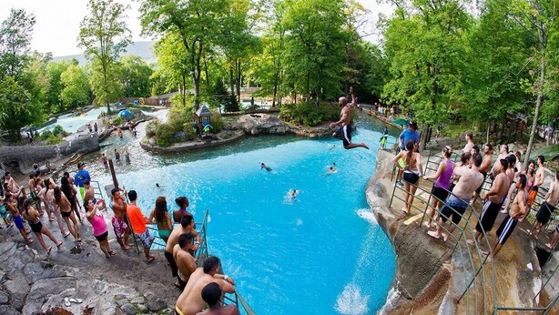 A natural pool surrounded by trees and rocky terrain, with people swimming and standing around. - Comfy Studio at the Appalachian building - Mountain Creek Resort, Vernon, NJ (Vernon)
