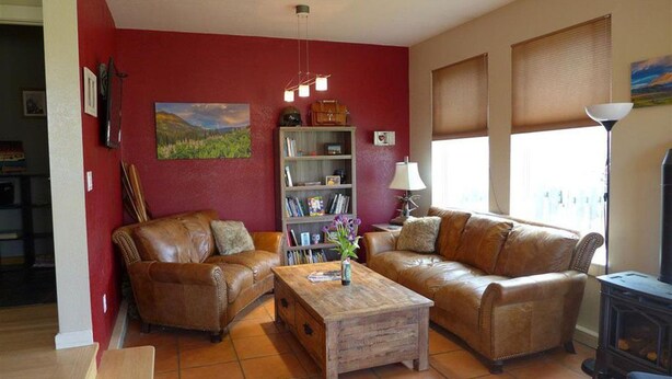 Ein Wohnzimmer mit zwei braunen Ledersofas, einem Holztisch, einem Bücherregal und einem Gemälde an der Wand.
