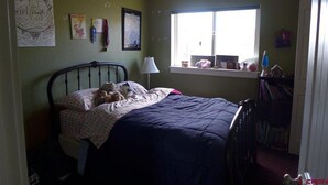 Ein Schlafzimmer mit Bett, Fenster und Bücherregal.
