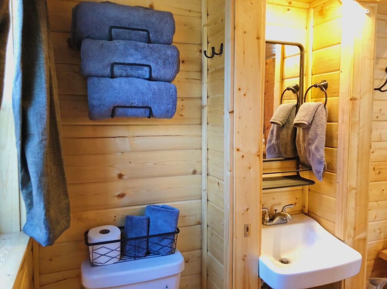 Un baño de cabaña de madera con inodoro, lavamanos y toallas.