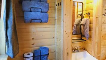 Un baño de cabaña de madera con inodoro, lavamanos y toallas.