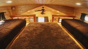 A cozy attic bedroom with two beds, a ceiling fan, and a large window. - A tiny cabin with big adventures (Forks)