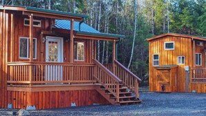 A wooden cabin with a porch and a staircase leading to the entrance. - A tiny cabin with big adventures (Forks)