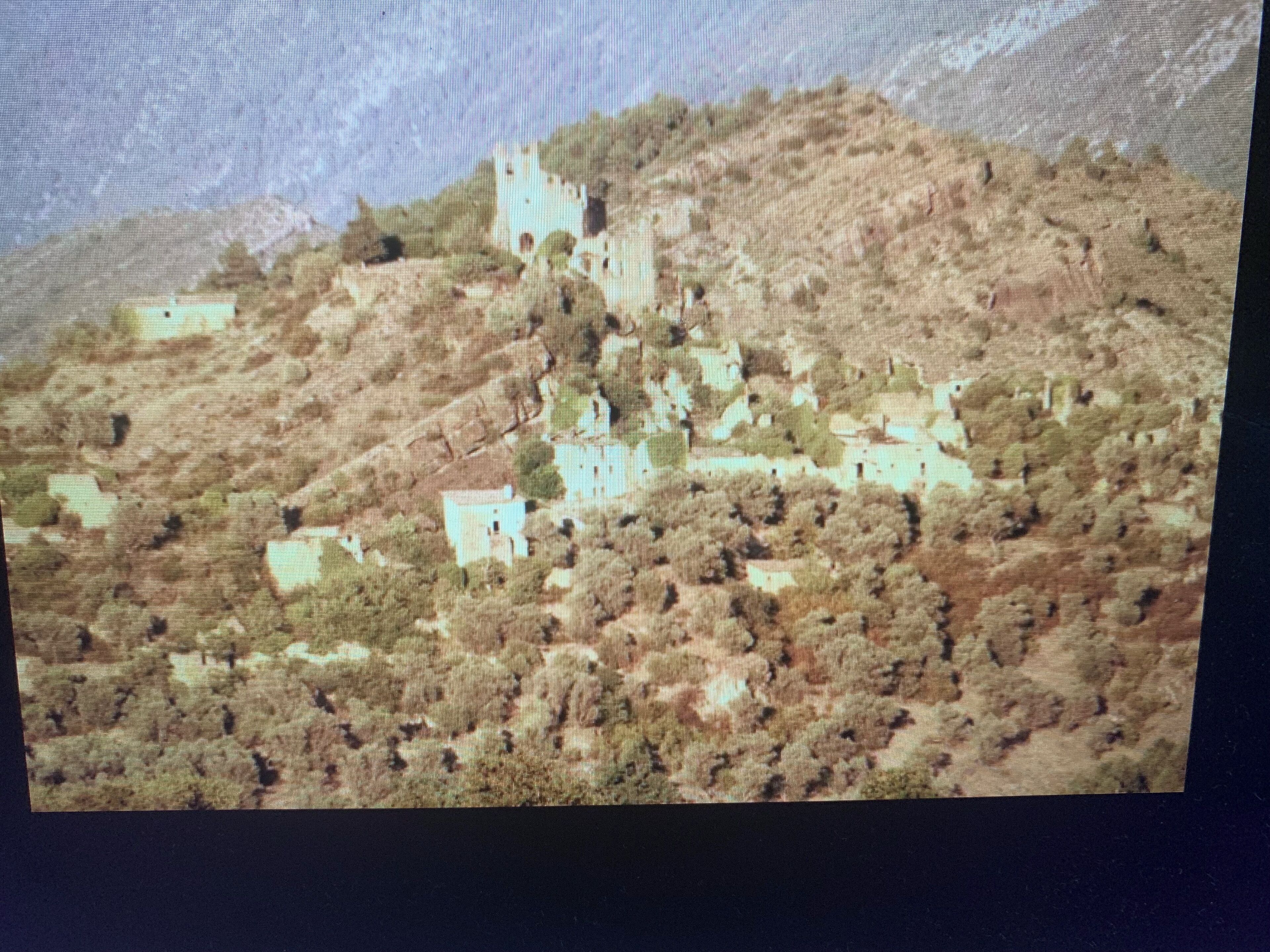A hilly landscape with several white buildings scattered across the terrain.