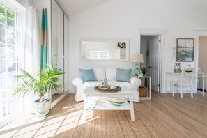 A bright living room with a white sofa, a coffee table, and a potted plant. - One bedroom fully equipped Mahone Bay luxury cottage (Mahone Bay)
