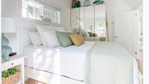 Une chambre à coucher avec un lit, une table de chevet, une lampe et une fenêtre donnant sur un beau paysage.