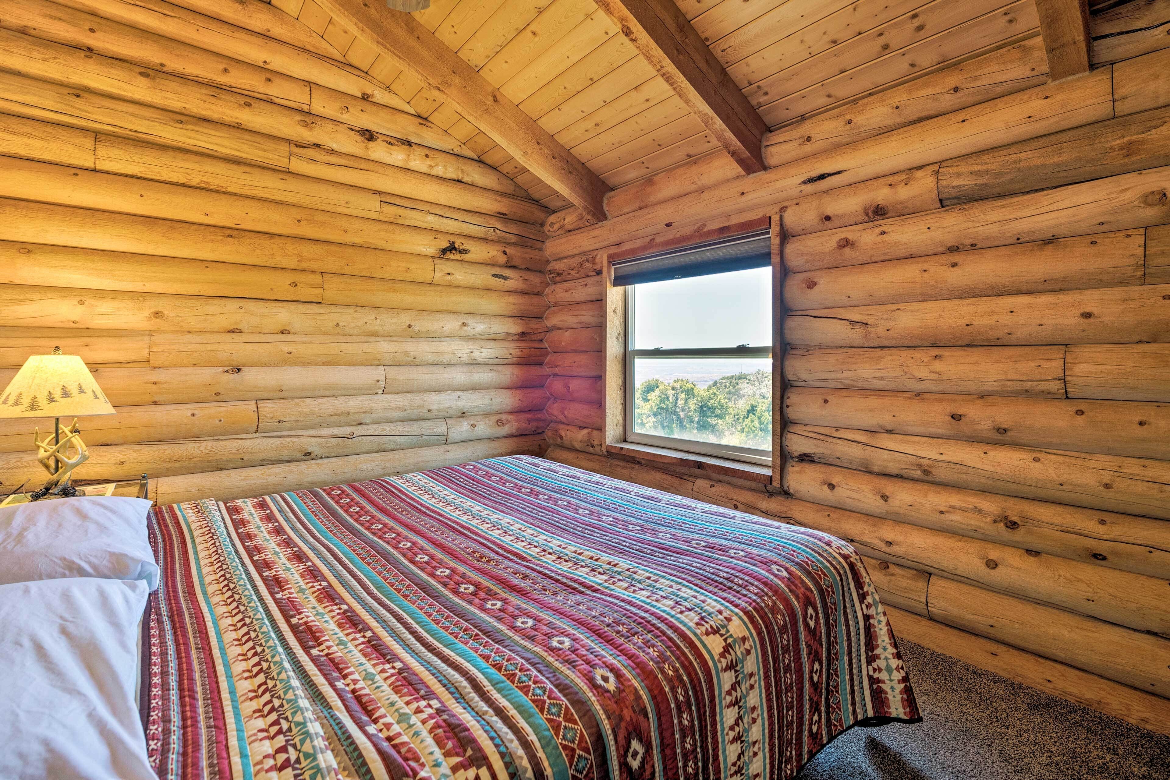 Una habitación tipo cabaña de madera con cama, ventana y lámpara.
