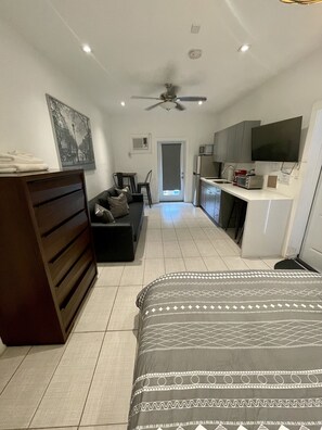 Relax in a cozy space with a neatly arranged bed, dark dresser, and comfortable sofa.
