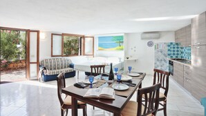 A modern kitchen with a tiled backsplash, a dining area with a table set for four, and a large window overlooking a garden.