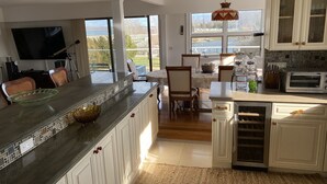 A modern kitchen with a large island, white cabinetry, and a view of the outdoors. - Bayfront Vacation Home in Southold, 5 Bedrooms (Southold)