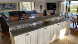 A modern kitchen with a large island, white cabinetry, and a tiled backsplash. - Bayfront Vacation Home in Southold, 5 Bedrooms (Southold)
