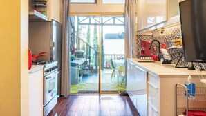 A compact kitchen with a stove, oven, and a TV on a counter. - Walkable Urban Retreat - 2 En-Suite Baths - Near Top Dining & Shops & Hotspots! (SF)