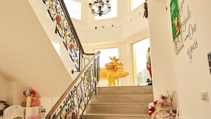 Una escalera con barandales negros ornamentados, escalones de madera y un candelabro.
