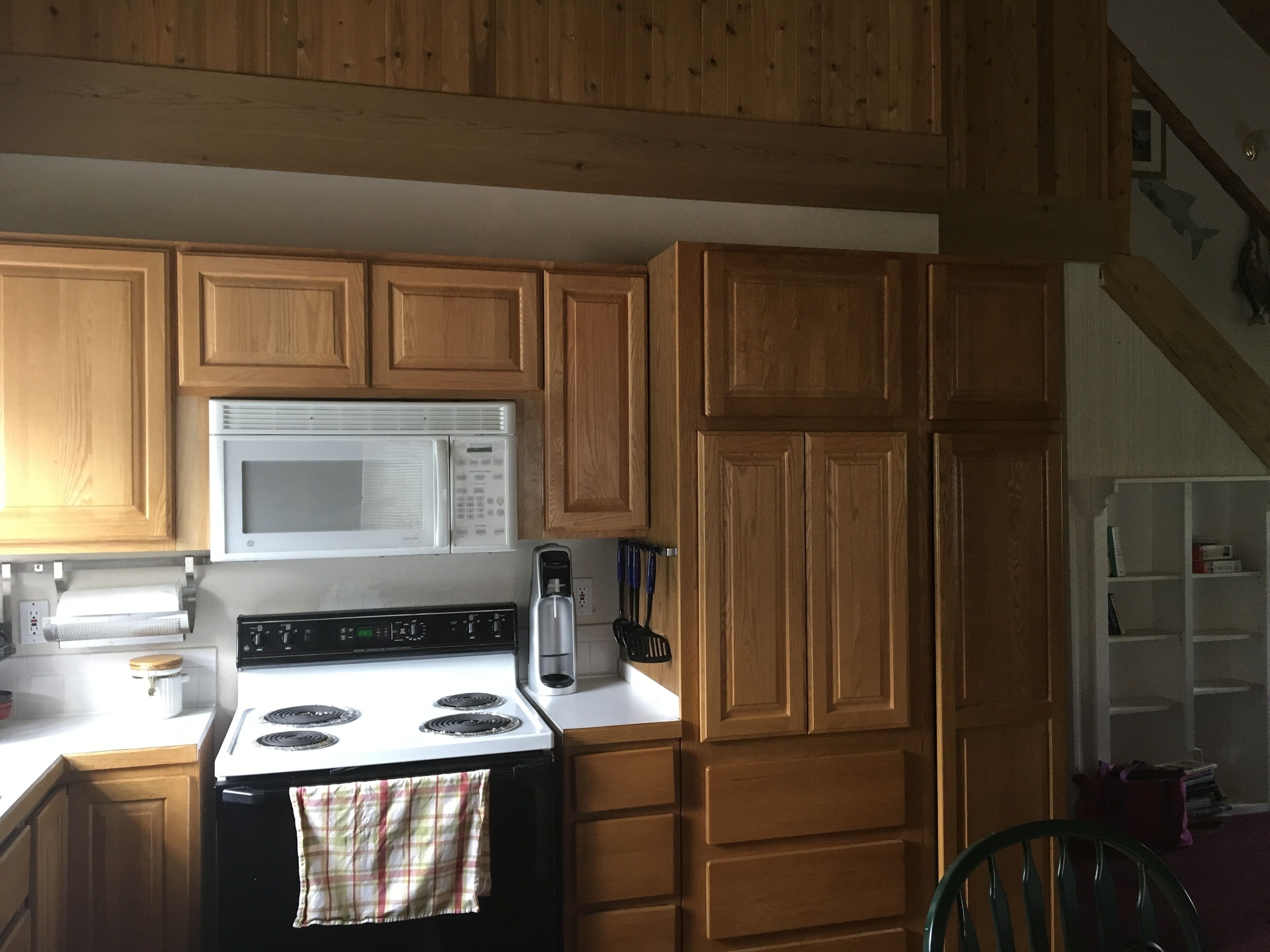 A kitchen with wooden cabinets, a white microwave, a stove, and a coffee maker.