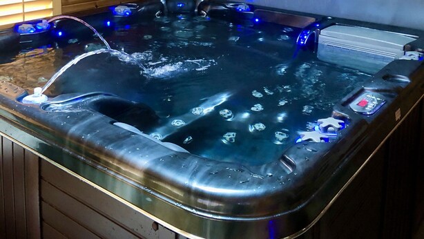 A hot tub with a wooden interior, a ceiling fan, and a window with blinds.