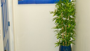 A hallway with a blue bear head decoration, a triptych painting of a lake, and a bamboo plant in a blue pot.