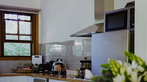 Una cocina moderna con lavavajillas, horno y microondas integrados. Se aprecia una ventana con vistas a zonas verdes.