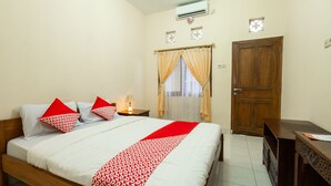Een slaapkamer met een houten bed, een nachtkastje met een lamp, een kledingkast en een raam met gordijnen.