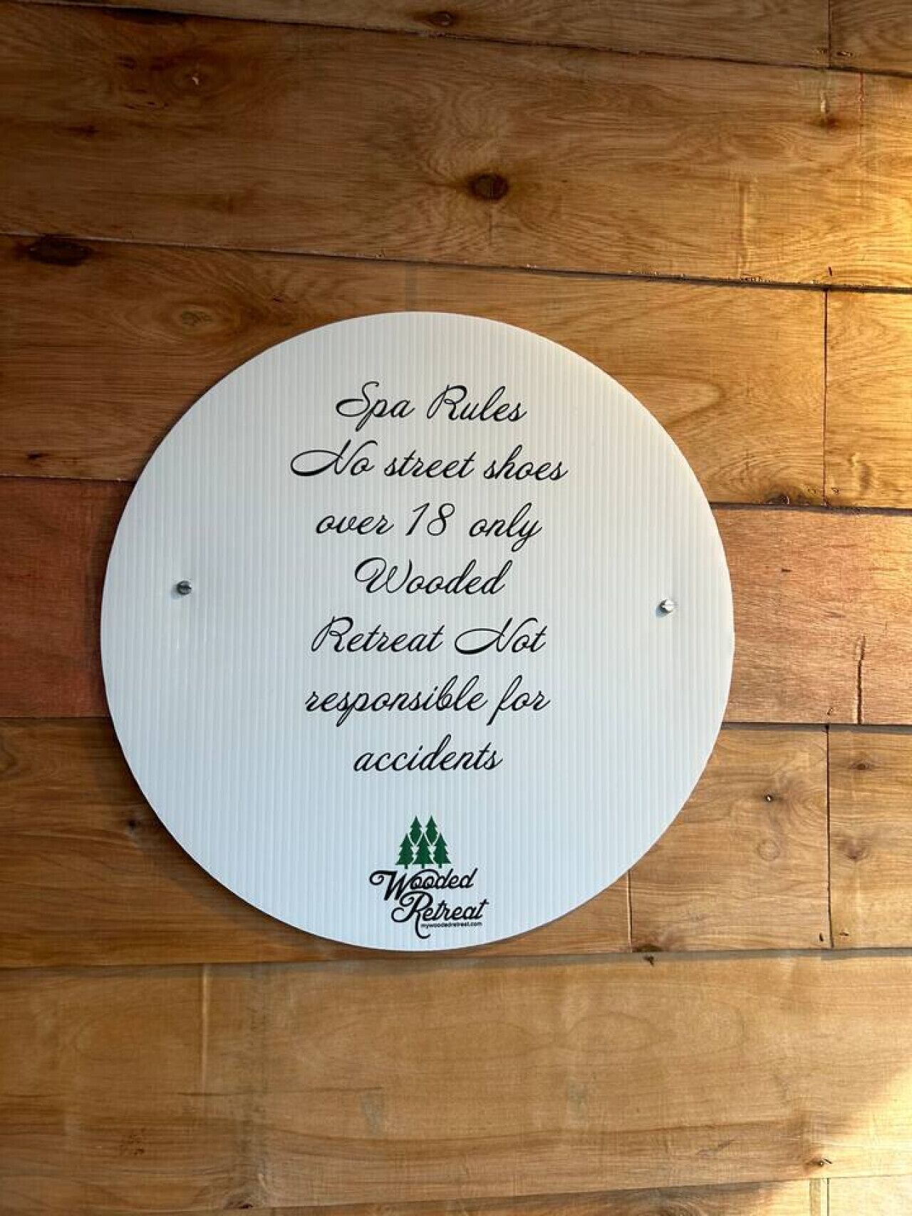 Señal circular con normas del spa en una pared de madera.