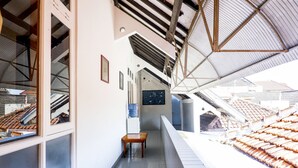 A corridor with a tiled floor, a wooden table, and a view of a traditional tiled roof. - OYO 1196 Hotel Pura Puspa Rosa (Depok)