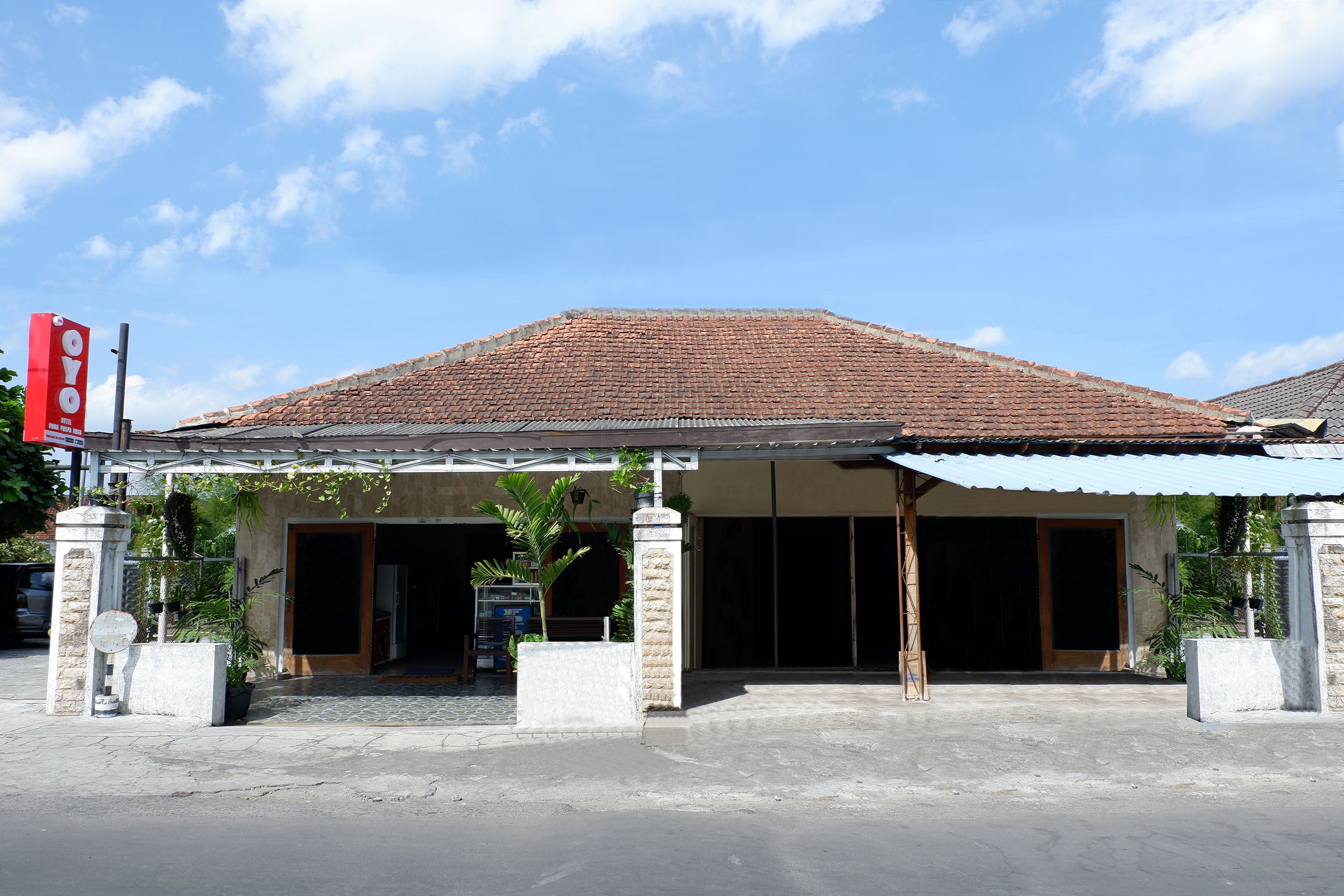 A building with a tiled roof, a covered entrance, and a signboard.