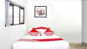 A bedroom with a bed, white walls, a window with curtains, and a framed picture on the wall. - OYO 1196 Hotel Pura Puspa Rosa (Depok)
