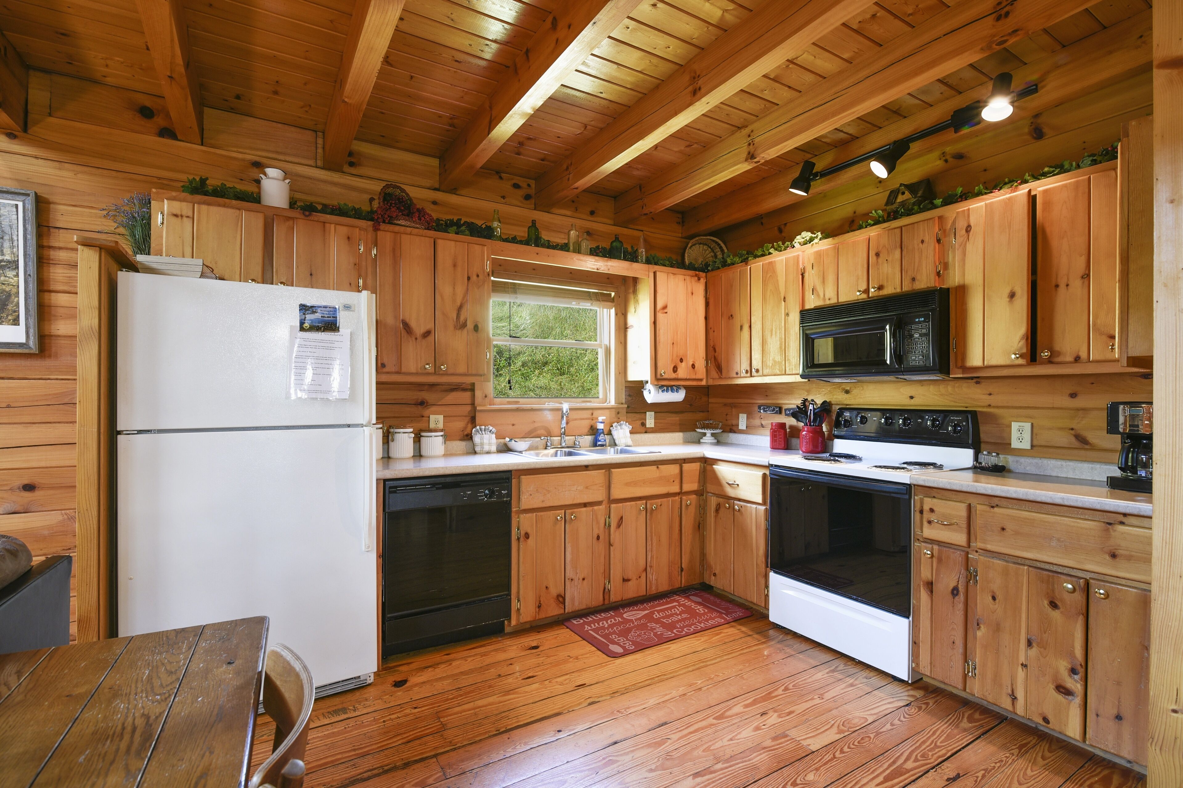 A wooden cabin kitchen with a refrigerator, stove, microwave, and wooden cabinets.