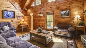 Ein gemütliches Blockhaus-Interieur mit Holzwänden, einer Couch, einem Couchtisch und zwei gerahmten Bildern.