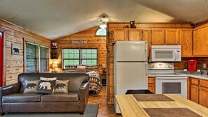 Interior acogedor de una cabaña con detalles de madera, un comedor y una cocina equipada con refrigerador y microondas.