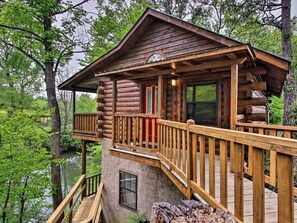 A log cabin with a wooden deck, a glass door, and a window.