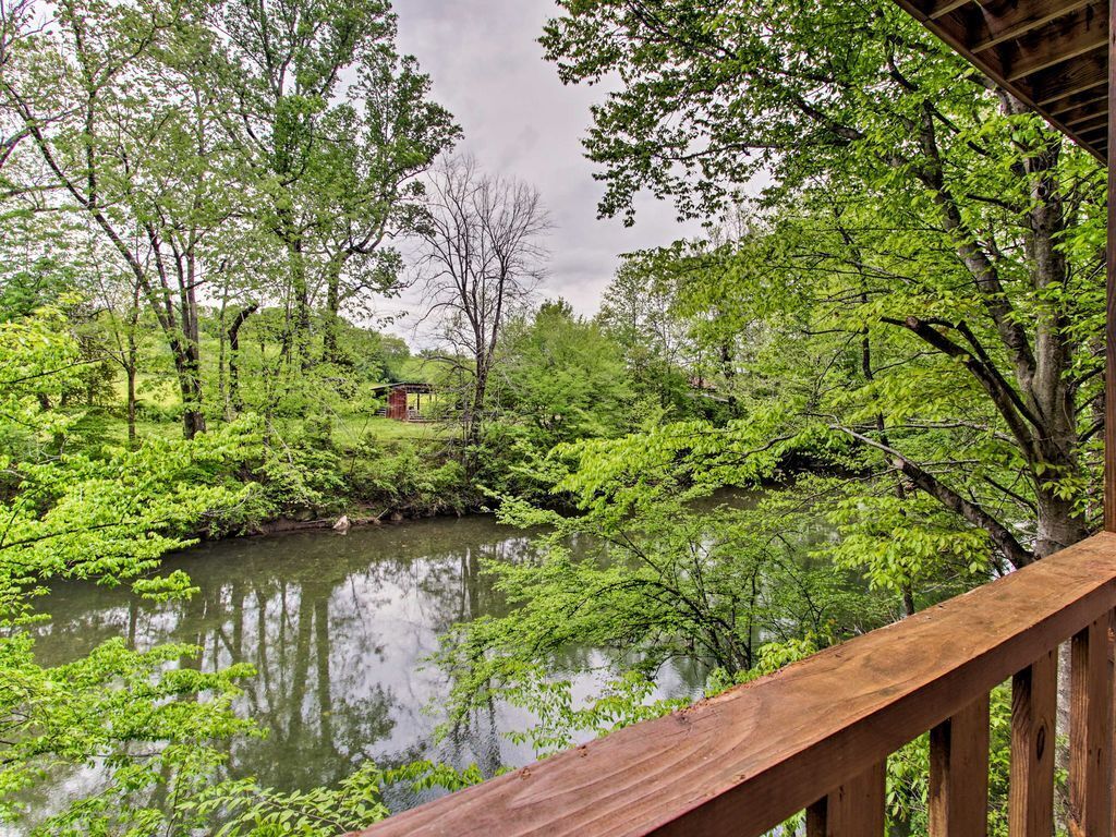 A wooden deck overlooking a calm river with lush greenery and trees.