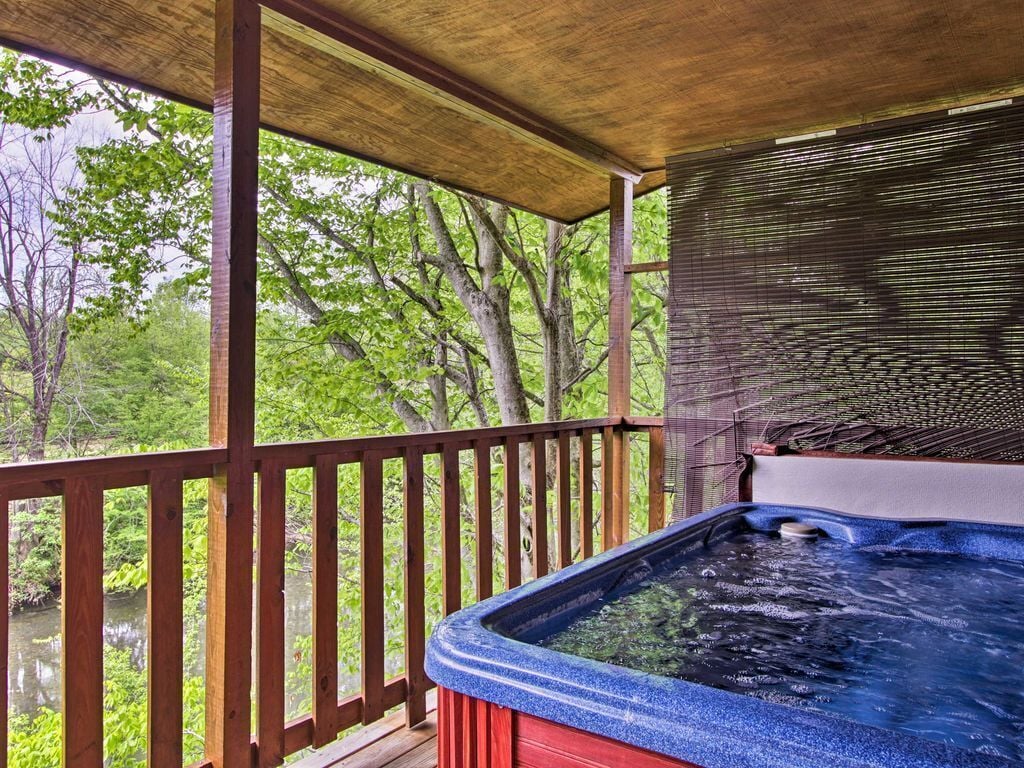 A hot tub on a wooden deck with a view of a forested area.