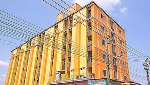 Un edificio de varios pisos con fachada amarilla y varios balcones.