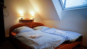 Een tweepersoonsbed met twee kussens en een dekbed, een houten hoofdbord en twee wandlampen.