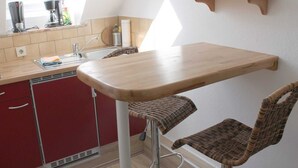 Een keuken met een houten tafel, rieten stoelen, een gootsteen en een raam.