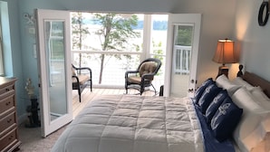 A bedroom with a large bed, a ceiling fan, a view of a balcony, and a chair. - Douglas Lake Retreat Private Dock + Boat (Sevierville)