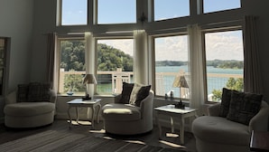 A spacious living room with large windows offering views of a lake and hills. - Douglas Lake Retreat Private Dock + Boat (Sevierville)