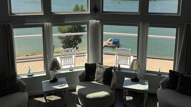 A spacious living room with large windows overlooking a lake and a deck area. - Douglas Lake Retreat Private Dock + Boat (Sevierville)