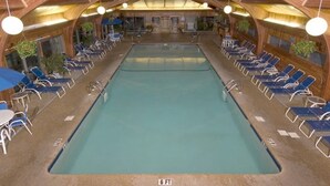 An indoor pool with a wooden ceiling and lounge chairs around the perimeter.