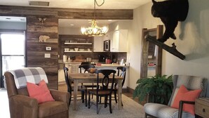 A cozy living room with a fireplace, a dining area with a chandelier, and a kitchen with modern appliances.