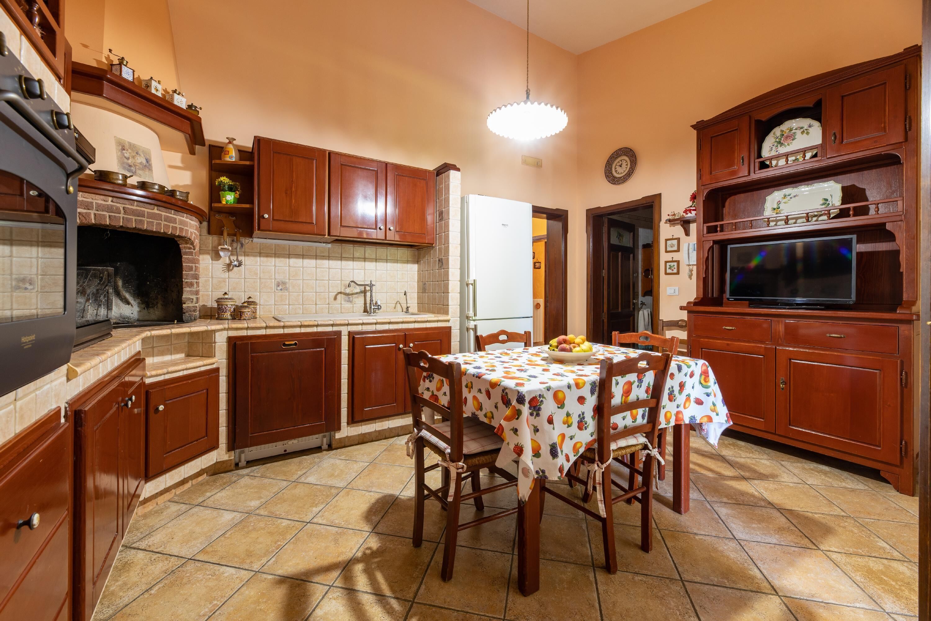Une cuisine avec des meubles en bois, un pare-feu en carrelage, un four encastré et une table à manger avec des chaises.