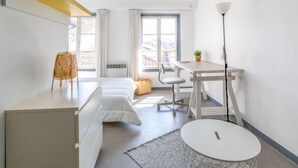 A modern, well-lit room with a bed, desk, chair, and a small table with a plant. - Casa Itzuli by Interhome (Bayonne)