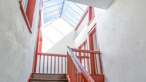 A wooden staircase with red railings leading to a room with a skylight. - Casa Itzuli by Interhome (Bayonne)